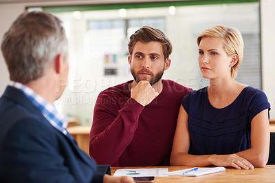 Buy stock photo Young couple discussing investment plans with a financial advisor