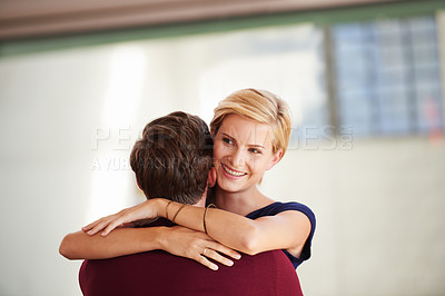 Buy stock photo Shot of a couple hugging together in an open office