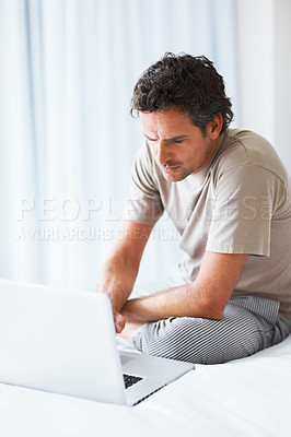 Buy stock photo Serious, man and remote work on laptop in bedroom to check email, reading digital news post and social network at home. Freelancer, typing and computer on bed in the morning to research information 