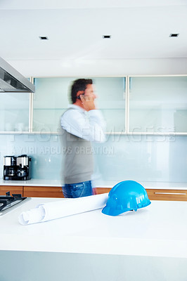 Buy stock photo Architect, phone call and blur of man talking in conversation for building project development in kitchen. Engineer, busy and discussion for construction on mobile with helmet and blueprint in home