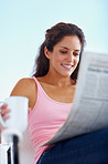 Young attractive woman reading newspaper