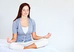 Peaceful cute female meditating in a lotus position in bed