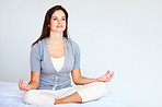 Smiling cute woman meditating in a lotus position in bed