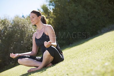 Buy stock photo An attractive woman sitting on the grass and meditating