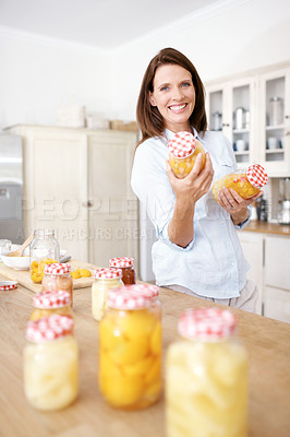 Buy stock photo A mature woman holding two jars in the kitchen