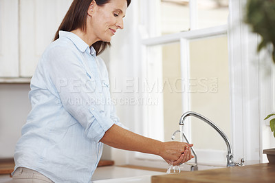 Buy stock photo An attractive woman washing her hands by the kitchen sink