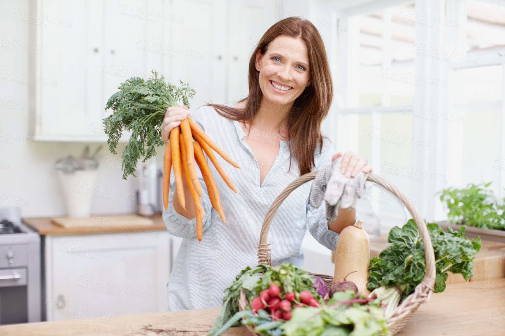 Buy stock photo Portrait, woman and organic carrots on kitchen table with gardening, growth and vegetables in basket. Female person, gardener and nutrition for diet, healthy food and sustainability in house