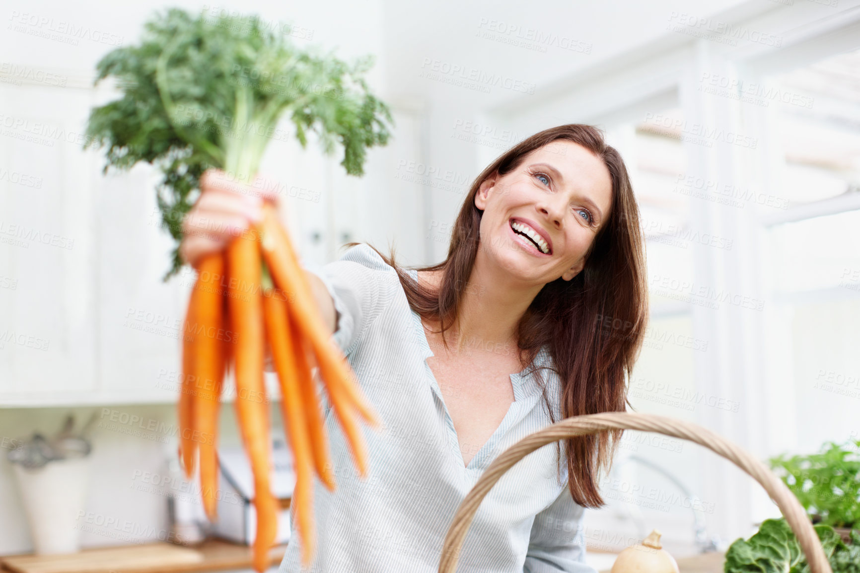 Buy stock photo Excited, woman and fresh carrots on kitchen table with gardening, growth and vegetables in basket. Female person, gardener and nutrition for diet, healthy eating and sustainability in agriculture