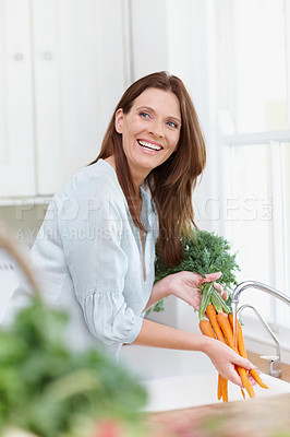 Buy stock photo A beautiful woman rinses her freshly picked carrots