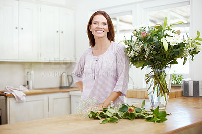 Buy stock photo Portrait of a beautiful woman arranging a bouquet of flowers at home