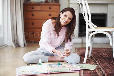 Buy stock photo Portrait of an attractive brunette working on a scrapbook while sitting on the floor in a home interior