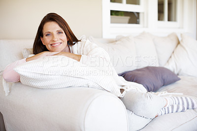 Buy stock photo Portrait of an attractive woman lounging on a sofa indoors