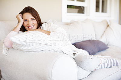 Buy stock photo A happy and attractive woman lounging on a sofa indoors