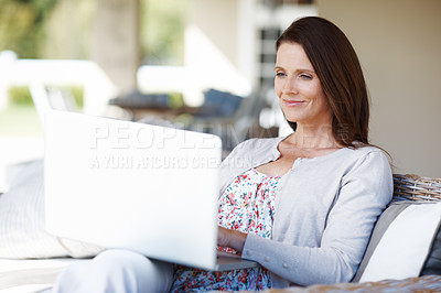 Buy stock photo An attractive woman working on a laptop while sitting outdoors