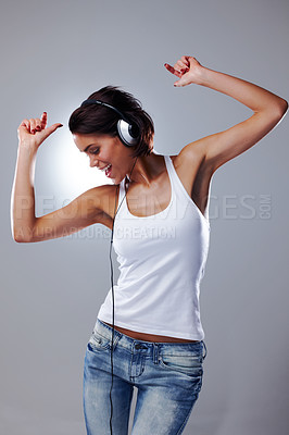 Buy stock photo Music, dance and woman with headphones in studio with trendy clothes, style and casual outfit. Dancer, happy and person listening to audio track, song and radio for movement on gray background