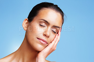 Buy stock photo Closeup portrait of a pretty young woman relaxing against blue background