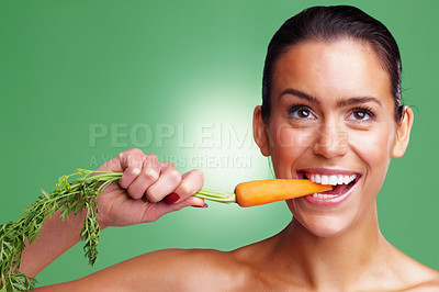Buy stock photo Closeup portrait of a smiling young woman eating carrot against green background