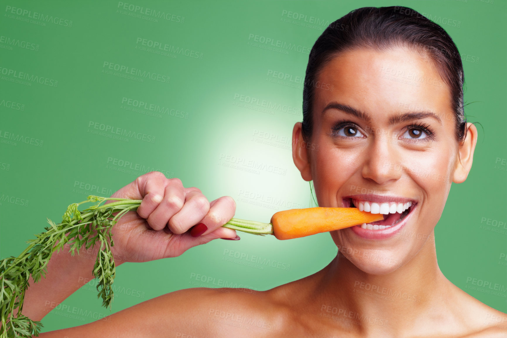 Buy stock photo Closeup portrait of a smiling young woman eating carrot against green background