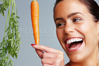 Buy stock photo Closeup of a cheerful young woman with fresh carrot against colored background