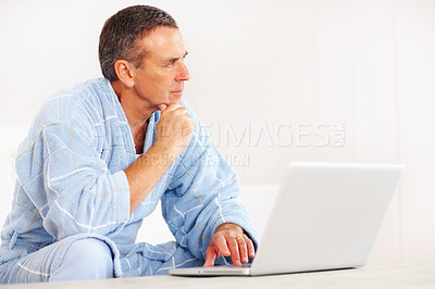 Buy stock photo Thinking, morning and senior man on laptop for email, social media or streaming subscription on sofa. Internet search, couch and mature person on computer, website or networking in bathrobe in home.