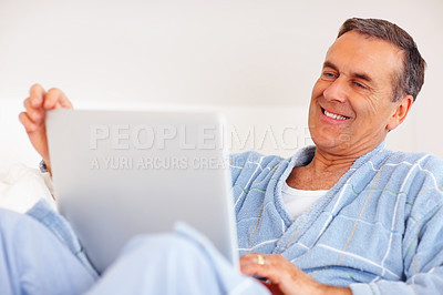 Buy stock photo Bathrobe, sofa and mature man on laptop for email, social media or streaming subscription in morning. Internet search, couch and senior person on computer with smile, website or networking in home.