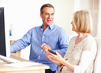 Mature couple calculating expenses with a computer on table