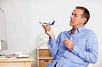 Senior man looking at toy plane as he plans for vacation