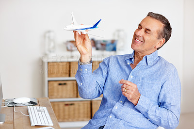 Buy stock photo Mature man, freedom and toy plane for travel, vacation and holiday planning with a smile at home. Happy, airplane model and retirement of a male person with thinking from trip and air traveling