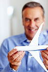 Happy senior man holding toy plane in front of you