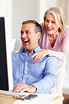 Cheerful mature man with wife working on computer