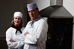 Two confident chefs with hands folded in commercial kitchen