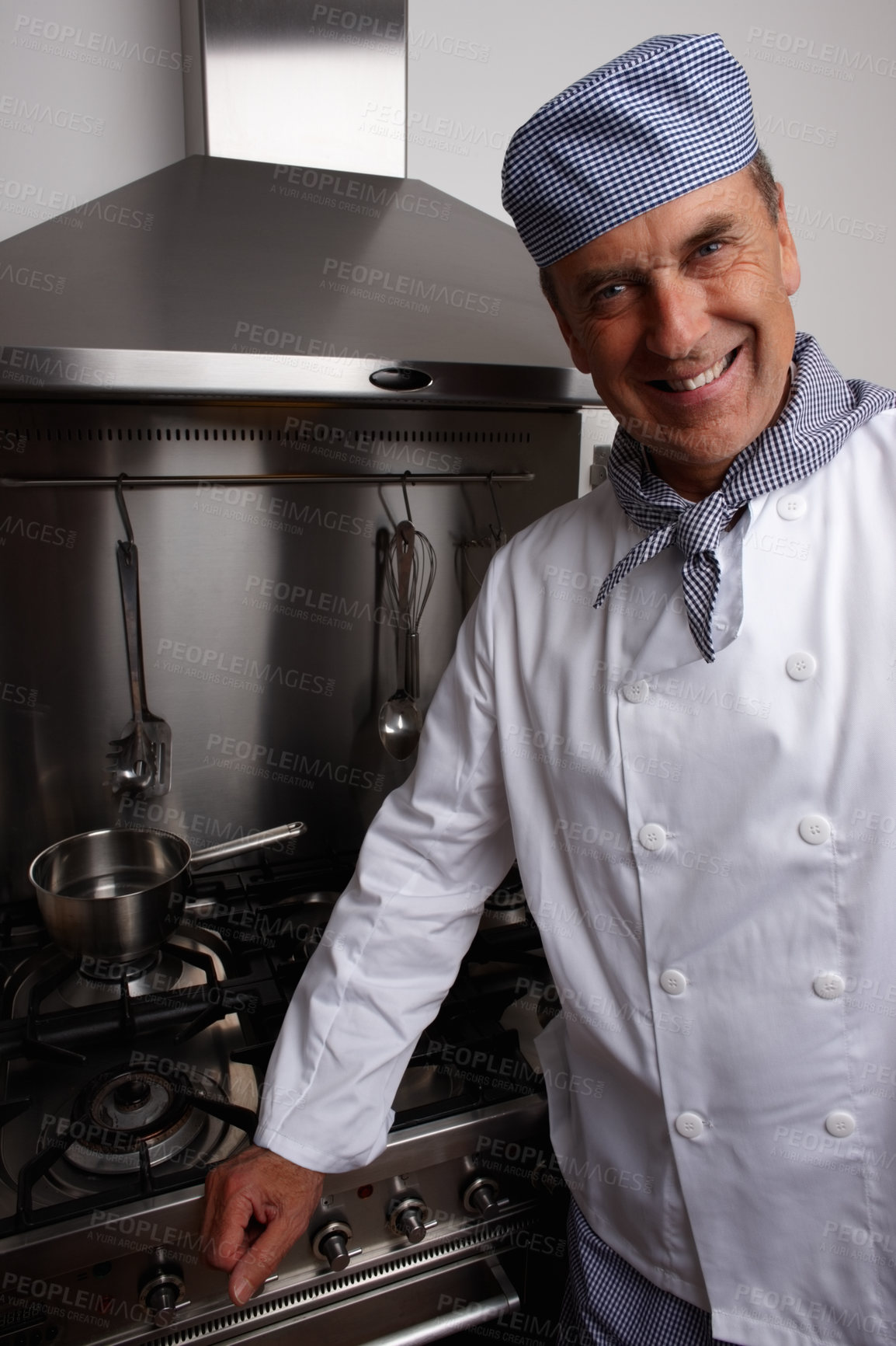 Buy stock photo Portrait of a smiling senior chef standing by gas stove and vent hood