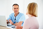 Mature doctor with laptop on desk consulting female patient