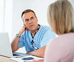 Serious medical doctor listening to female patient at clinic