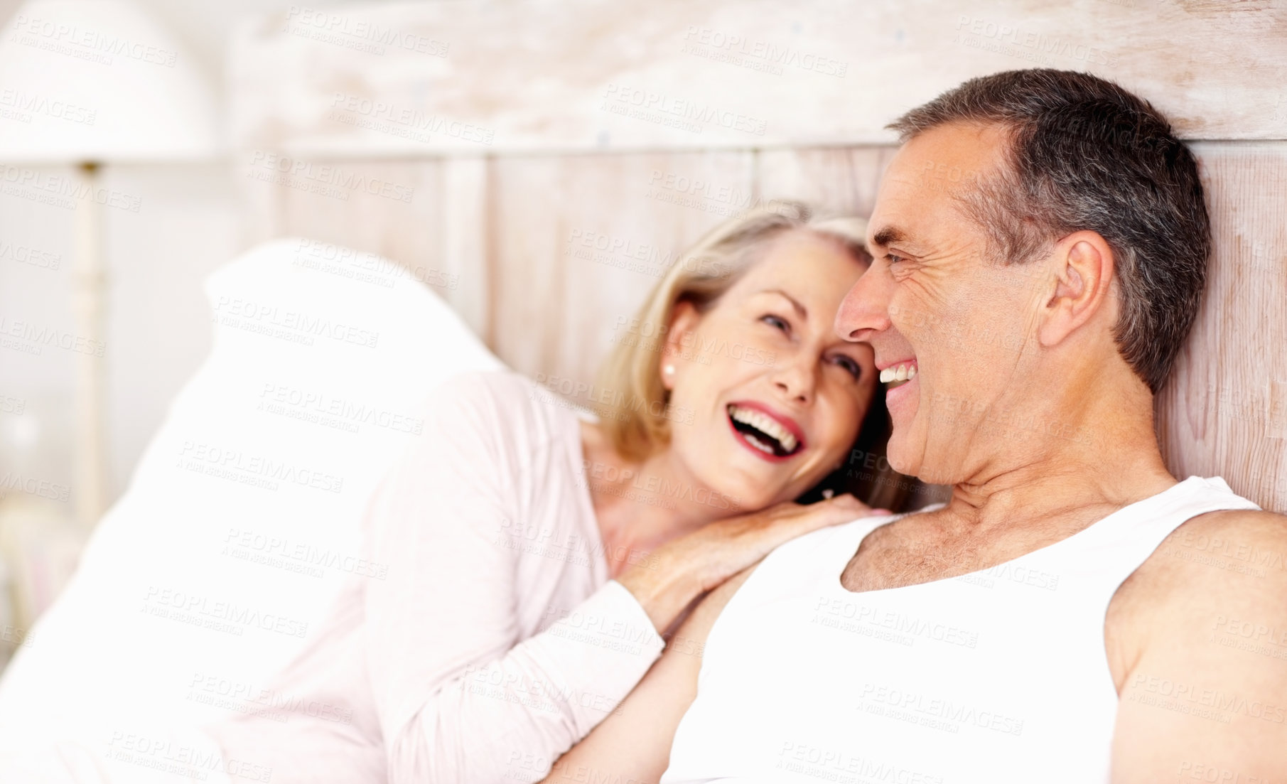 Buy stock photo Mature couple, laugh and relax in bed at house for hug, love and retirement together with trust and care. Man, woman and cuddle in hotel bedroom for marriage, loyalty or tired on weekend with smile