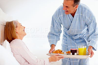 Buy stock photo Mature couple, serving and breakfast in home for nutrition, diet health and bonding time in bedroom. Smile, woman and  man with food tray for morning meal, romantic care and eating on bed mattress