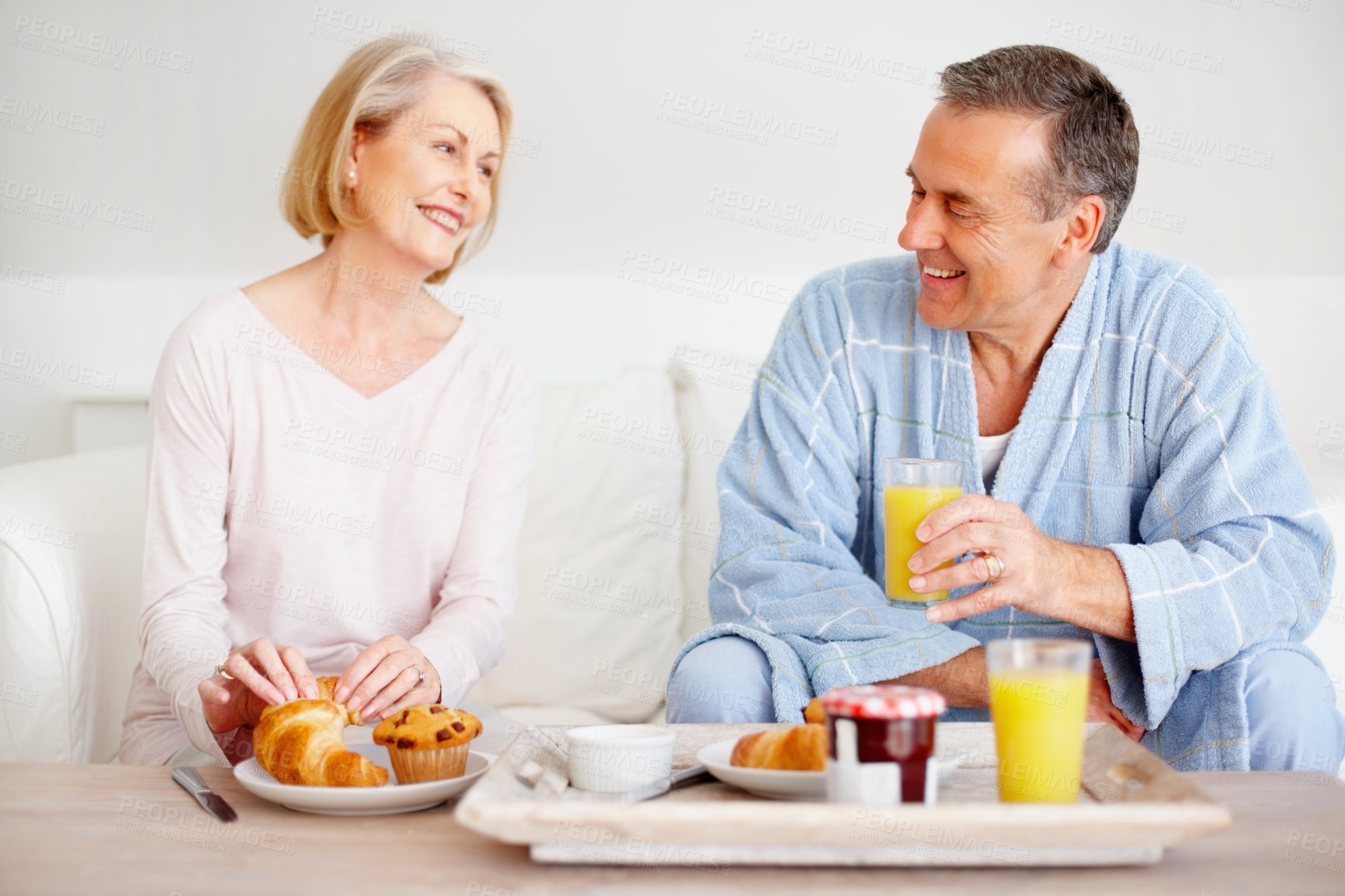 Buy stock photo Mature couple, happy and breakfast together on sofa with bonding, diet nutrition and support in home. Smile, man and woman with morning meal, healthy food and romantic time for love relationship