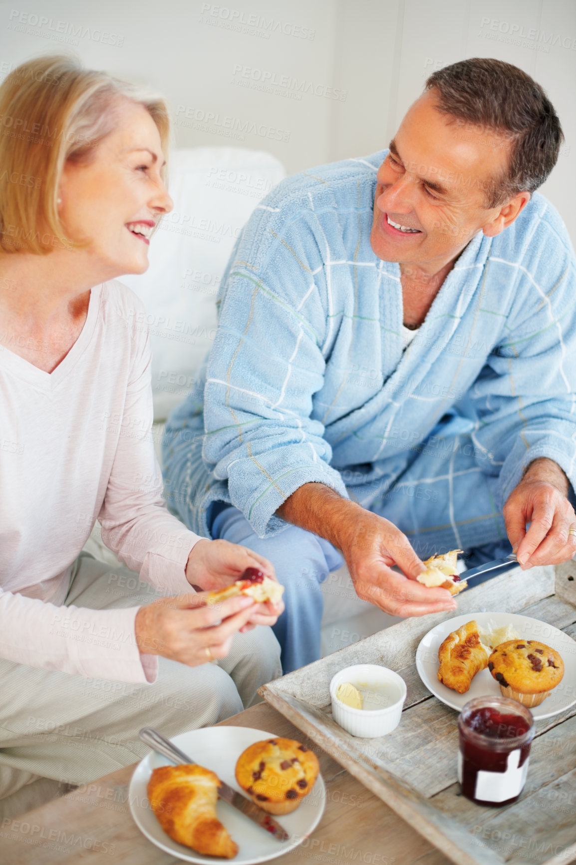 Buy stock photo Senior couple, bedroom and food for romance, breakfast and wellness for retirement health. Mature woman, man and croissant or muffin for meal with fruit jam for diet, nutrition and care for support