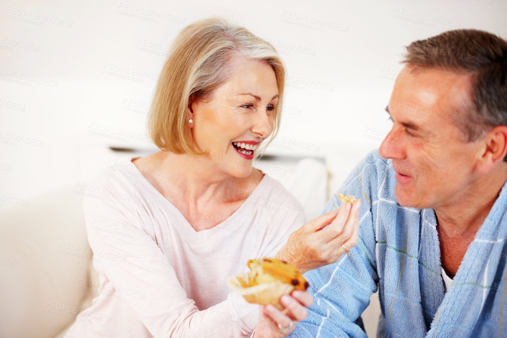 Buy stock photo Mature couple, bedroom and food for feeding, breakfast and nutrition for retirement health. Senior woman, man and croissant or muffin with baked good for diet, romance and elderly wellness or home