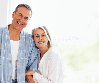 Buy stock photo Portrait, love and window with senior couple, hugging and support in living room of house together. Smile, face and trust with happy, mature man and woman bonding while enjoying retirement at home