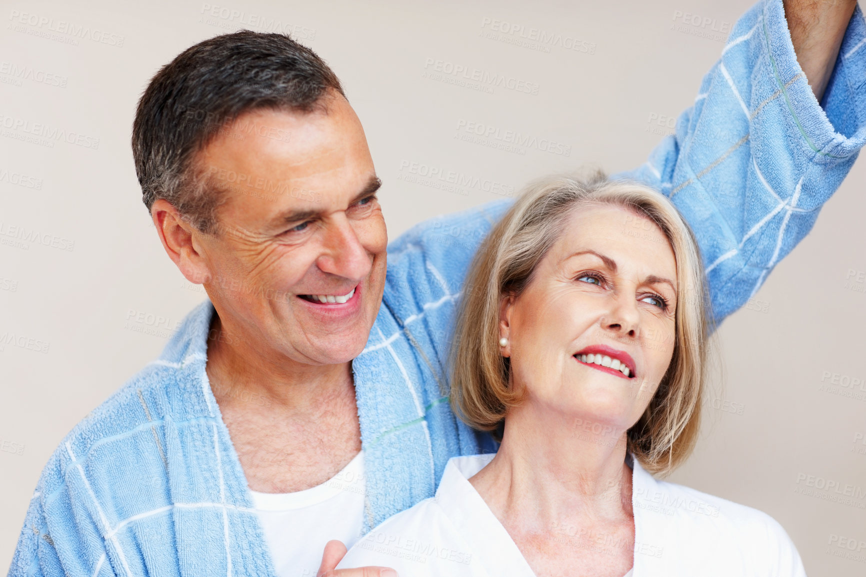 Buy stock photo Mature couple, smile and bonding in home with hug for retirement, leisure and wellness in gown. Man, woman and comfort in house for peace, health and relax with embrace, happiness and stress relief