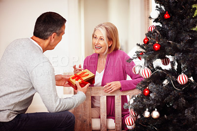 Buy stock photo Senior, happy couple and christmas tree with gift for surprise, offer or festive celebration at home. Mature man and woman with smile for present, ribbon box or December holiday together at house