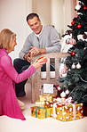 Happy mature couple looking at Christmas presents at home