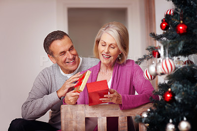 Buy stock photo Home, senior couple and gift box in christmas for surprise, celebration and bonding together in marriage. Happy people, man and woman in house for love, romance and care with present in relationship