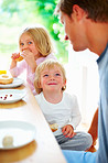 Smiling little boy with his father and sister having breakfast