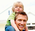 Happy mature man carrying his son in front of house