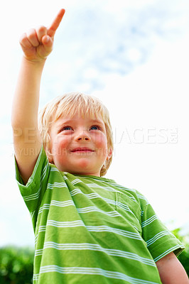 Buy stock photo Boy, child and pointing at space outdoor in low angle, summer mockup and show direction. Young cute kid, finger and hand gesture at blue sky clouds, park and nature garden, playing and freedom