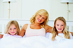 Loving middle aged woman with her two daughter in bed