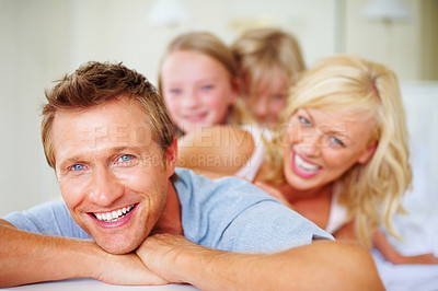 Buy stock photo Portrait, funny and a family lying on a bed together while in their home on a weekend morning. Face, love and father, mother and children laughing in the bedroom of an apartment to relax for bonding