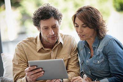 Buy stock photo Shot of a husband and wife using a digital tablet together at home